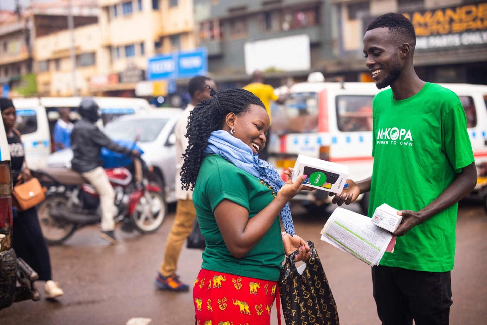 M-KOPA agent handing a phone to a customer in Africa